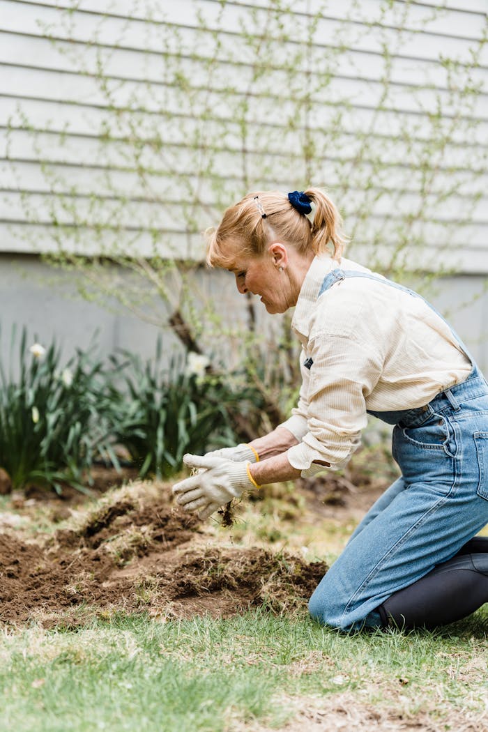Woman tending to garden, preparing soil for spring planting.